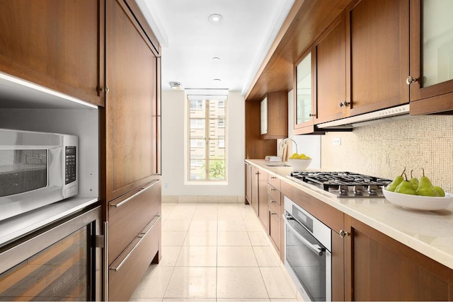 kitchen featuring appliances with stainless steel finishes, wine cooler, sink, backsplash, and light tile patterned flooring