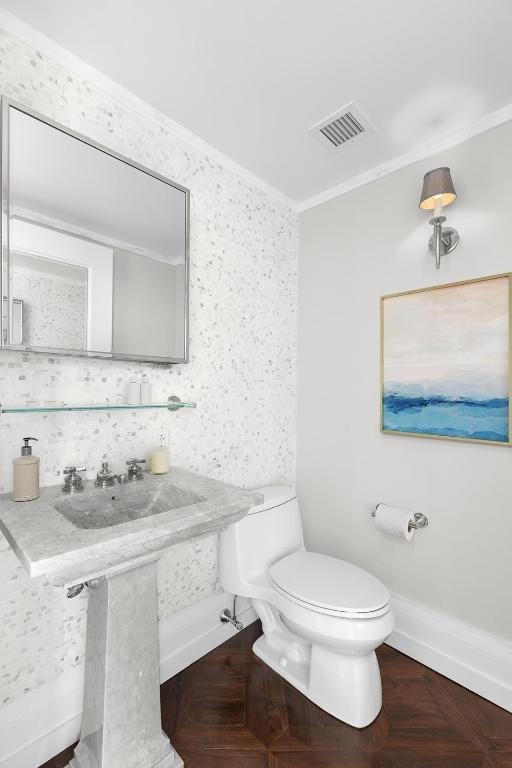 bathroom with toilet, ornamental molding, parquet floors, and tasteful backsplash