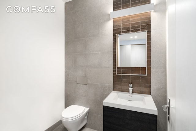 bathroom with toilet, vanity, tile walls, and decorative backsplash