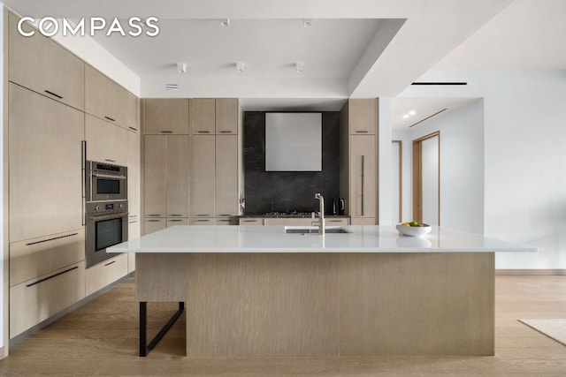 kitchen featuring sink, a large island, light brown cabinets, and light hardwood / wood-style floors