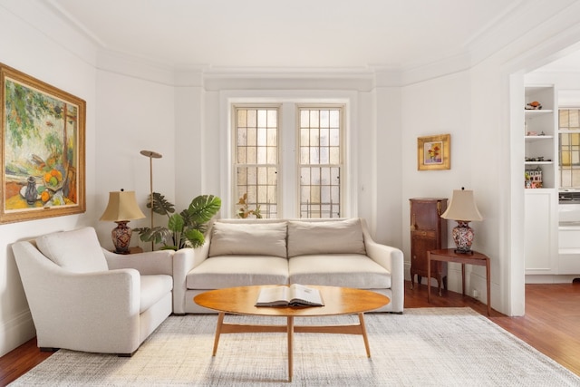 living area featuring crown molding and light hardwood / wood-style flooring