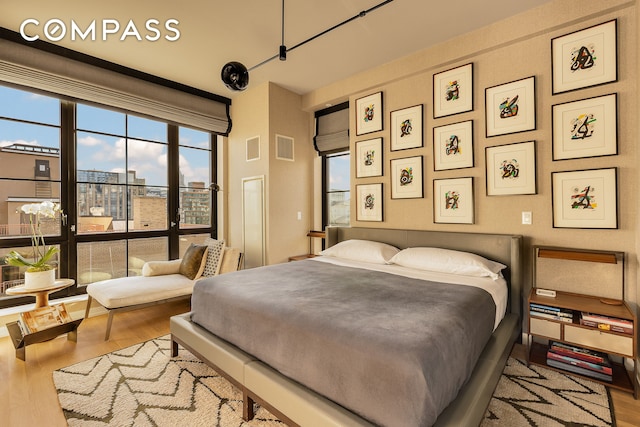 bedroom featuring visible vents, a city view, and wood finished floors