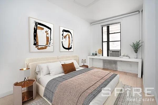 bedroom with cooling unit, baseboards, and wood finished floors