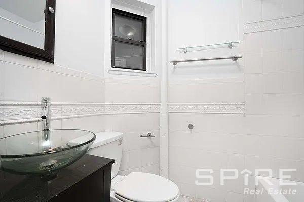 bathroom with vanity, tile walls, and toilet