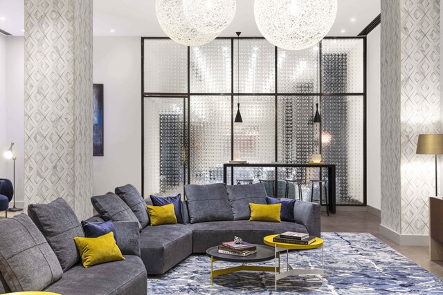 living room featuring an accent wall, floor to ceiling windows, a chandelier, and wood finished floors