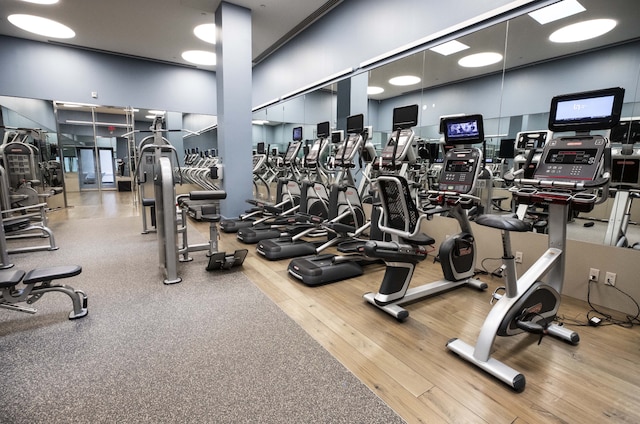 workout area featuring wood finished floors and a towering ceiling