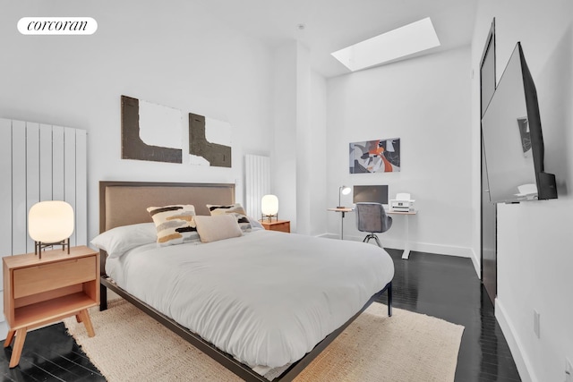 bedroom with a skylight, baseboards, and a towering ceiling