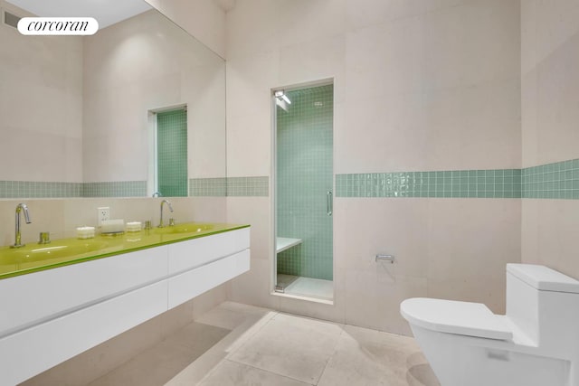 bathroom with a sink, tile walls, tile patterned flooring, and toilet