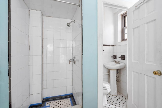 bathroom featuring sink, tile walls, tile patterned flooring, tiled shower, and toilet