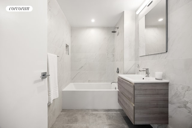 bathroom featuring tile walls, vanity, and tiled shower / bath combo