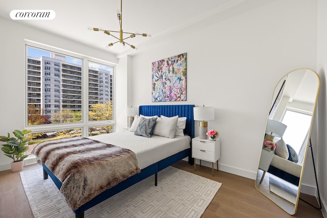 bedroom with an inviting chandelier, baseboards, visible vents, and wood finished floors