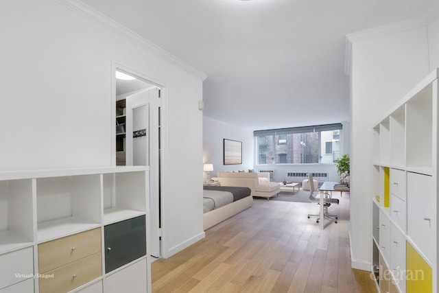 interior space featuring crown molding, radiator heating unit, and light wood-type flooring