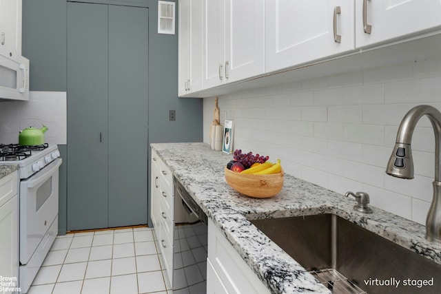 kitchen with decorative backsplash, sink, white appliances, white cabinetry, and light tile patterned floors