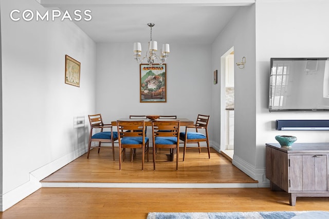 dining room with baseboards, light wood-style flooring, and an inviting chandelier