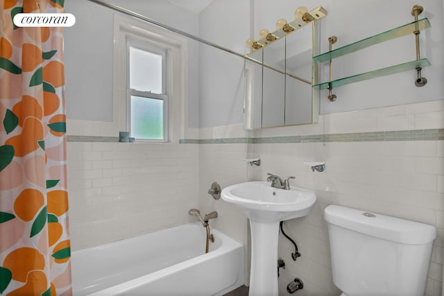 full bathroom featuring toilet, tile walls, shower / bathtub combination with curtain, and a wainscoted wall