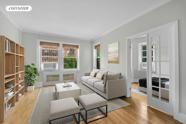 living room with ornamental molding, baseboards, visible vents, and light wood finished floors