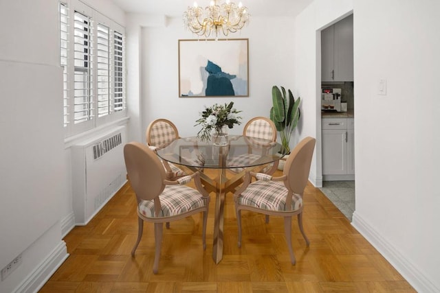 dining area with a notable chandelier, light parquet floors, and radiator heating unit