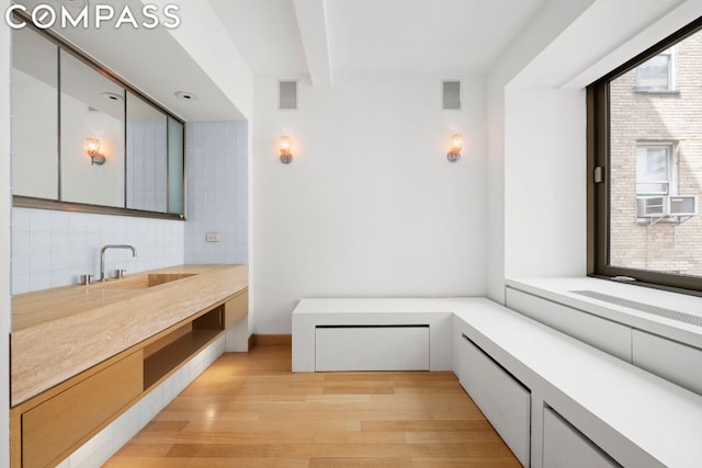 bathroom with hardwood / wood-style floors, vanity, beam ceiling, and tasteful backsplash