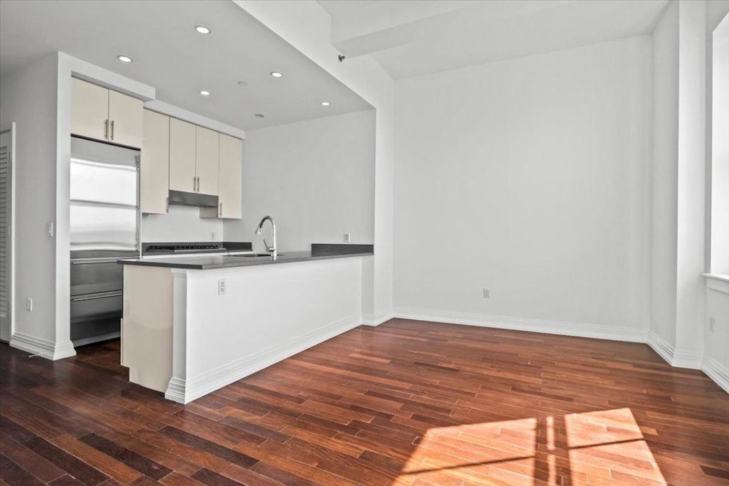 kitchen with built in refrigerator, kitchen peninsula, and sink