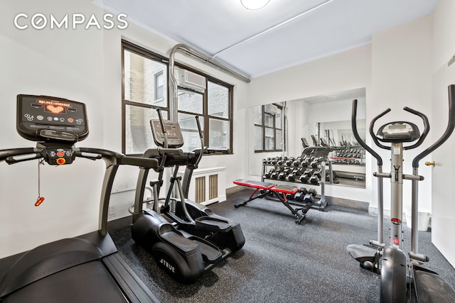 exercise room with crown molding, baseboards, and a wall mounted AC