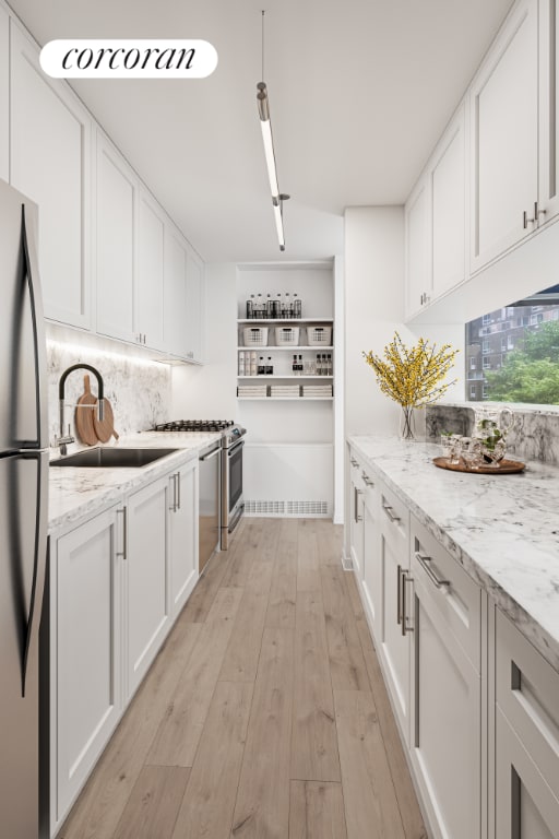 kitchen featuring sink, light hardwood / wood-style flooring, light stone countertops, white cabinets, and stainless steel fridge