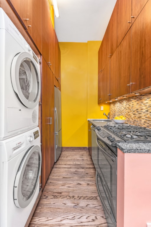 laundry area with light hardwood / wood-style floors, sink, and stacked washer and dryer