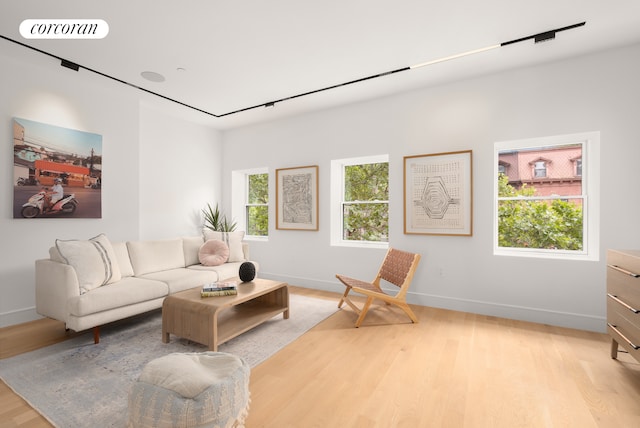 living area featuring a healthy amount of sunlight, visible vents, baseboards, and light wood finished floors