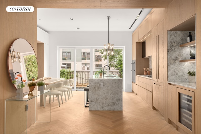 kitchen featuring modern cabinets, beverage cooler, a center island with sink, and light brown cabinetry