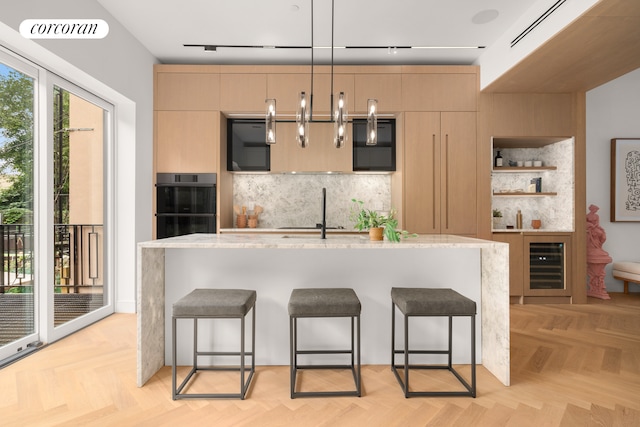 kitchen featuring visible vents, dobule oven black, a sink, beverage cooler, and a kitchen breakfast bar