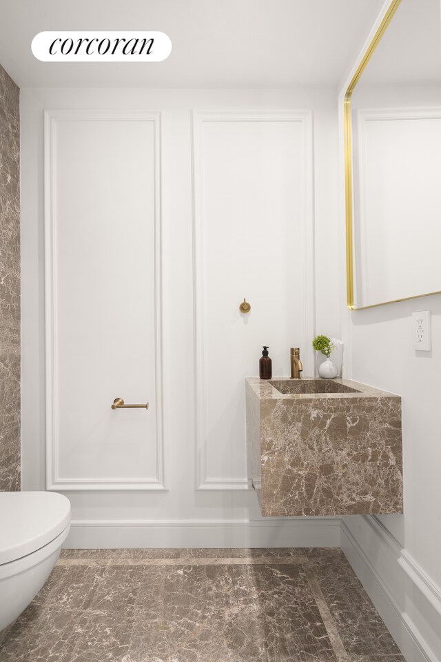 bathroom with marble finish floor and toilet