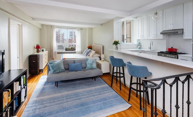 interior space with beamed ceiling, sink, and light hardwood / wood-style flooring