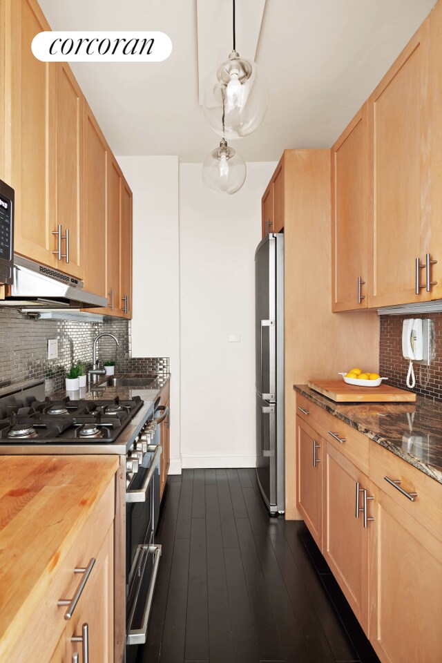 kitchen with light brown cabinetry, decorative light fixtures, tasteful backsplash, stainless steel appliances, and dark wood-type flooring