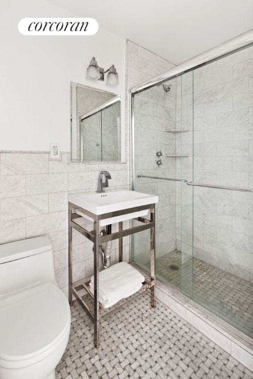 bathroom with tile patterned flooring, walk in shower, tile walls, and toilet