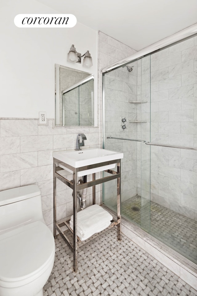 bathroom featuring toilet, tile patterned flooring, a shower stall, and tile walls