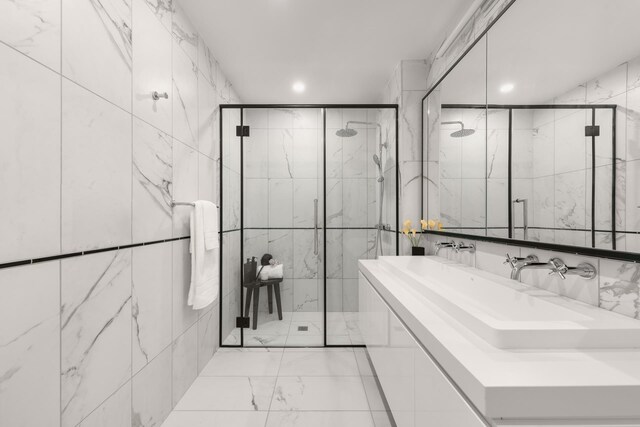 full bath featuring marble finish floor, a sink, recessed lighting, tile walls, and a shower stall