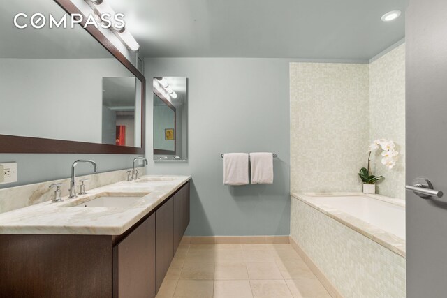 full bath featuring a bath, tile patterned flooring, double vanity, and a sink