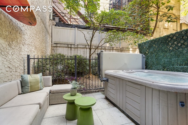 view of patio / terrace with a hot tub, fence, and an outdoor living space