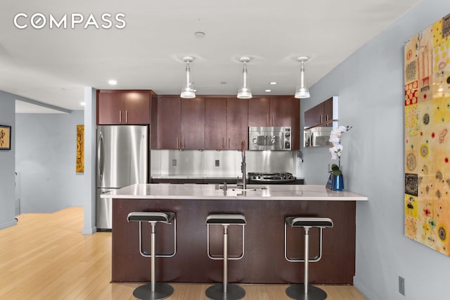 kitchen with a peninsula, a breakfast bar area, stainless steel appliances, and light countertops