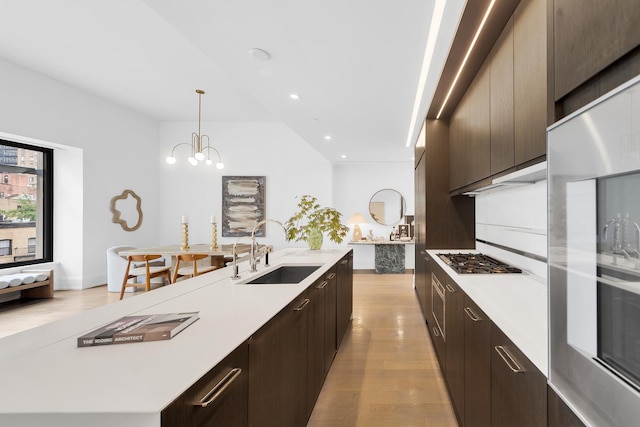 301 E 50th St Unit 4D, New York City, NY 10022 - kitchen featuring a sink, stainless steel gas cooktop, light wood-style floors, light countertops, and dark brown cabinetry