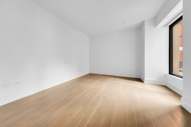 spare room with baseboards and wood finished floors