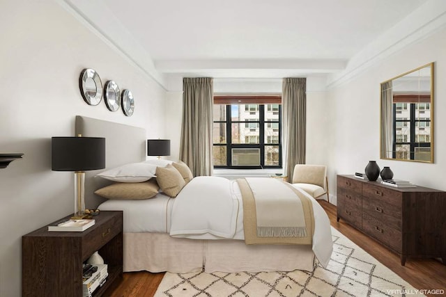 bedroom featuring wood finished floors and beamed ceiling