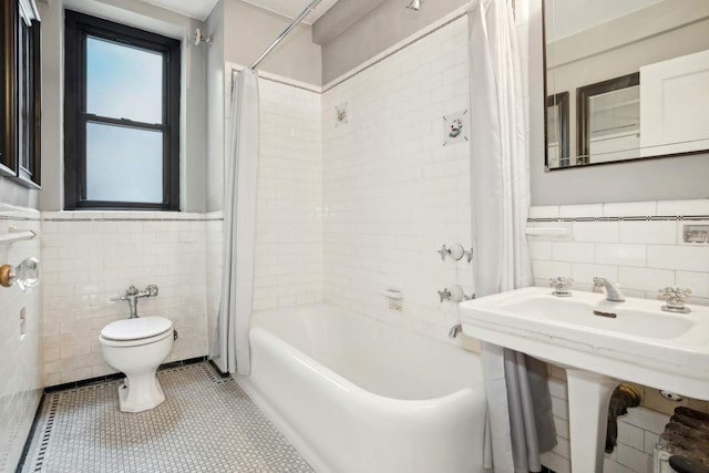 full bath featuring a wainscoted wall, tile walls, toilet, shower / tub combo, and tile patterned floors