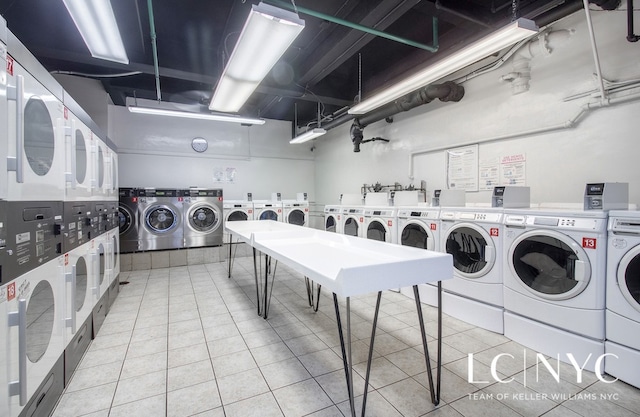 common laundry area featuring stacked washer / dryer, light tile patterned flooring, and washing machine and clothes dryer