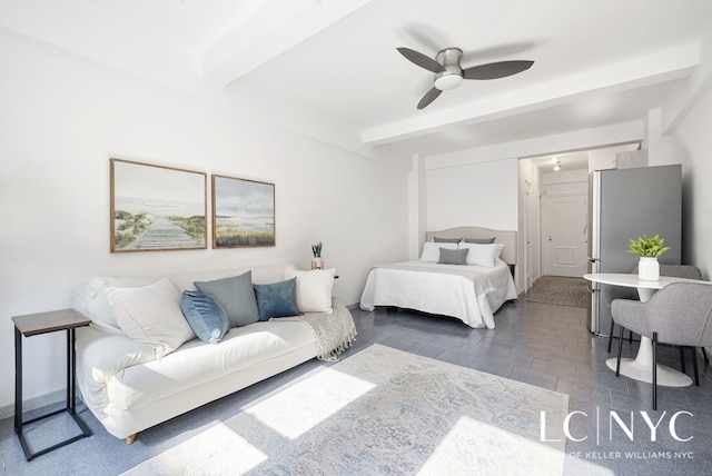 bedroom with stone finish floor, freestanding refrigerator, beamed ceiling, and a ceiling fan