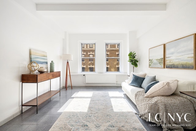 living area featuring radiator, granite finish floor, baseboards, and beam ceiling