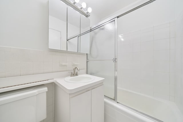 full bathroom with toilet, bath / shower combo with glass door, vanity, tile walls, and tasteful backsplash