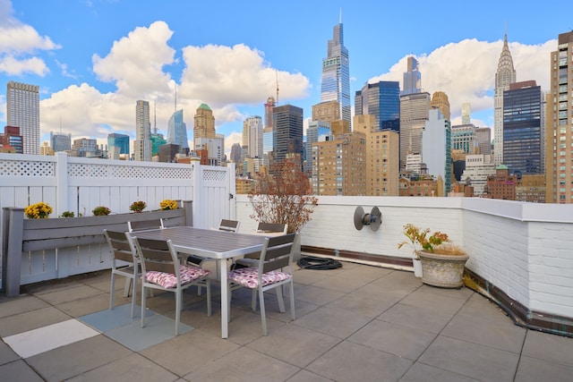 view of patio with outdoor dining area, a city view, and fence