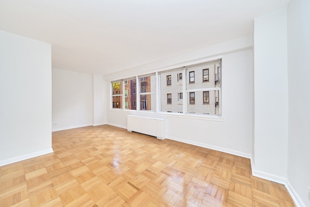 spare room with radiator heating unit and baseboards