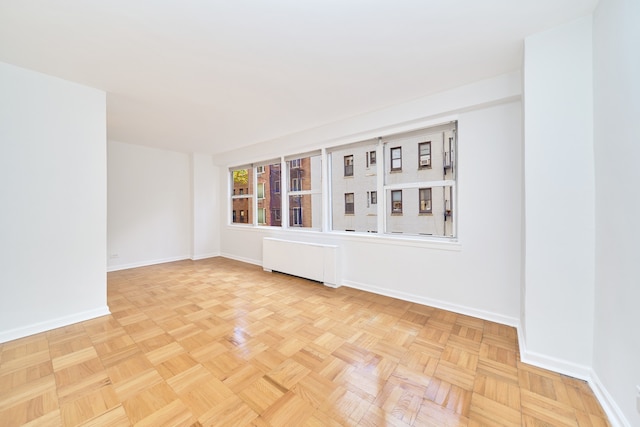 unfurnished room featuring radiator and baseboards