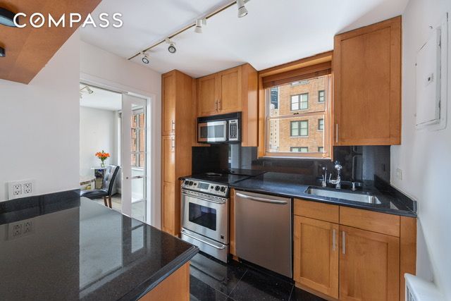 137 E 36th St Unit 6G, New York City, NY 10016 - kitchen with stainless steel appliances, a sink, brown cabinetry, rail lighting, and backsplash